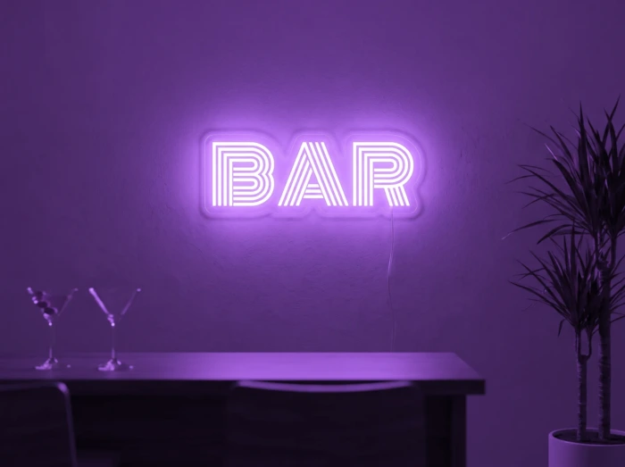 Neonskylt «BAR» i lila LED-neon, monterad på vägg