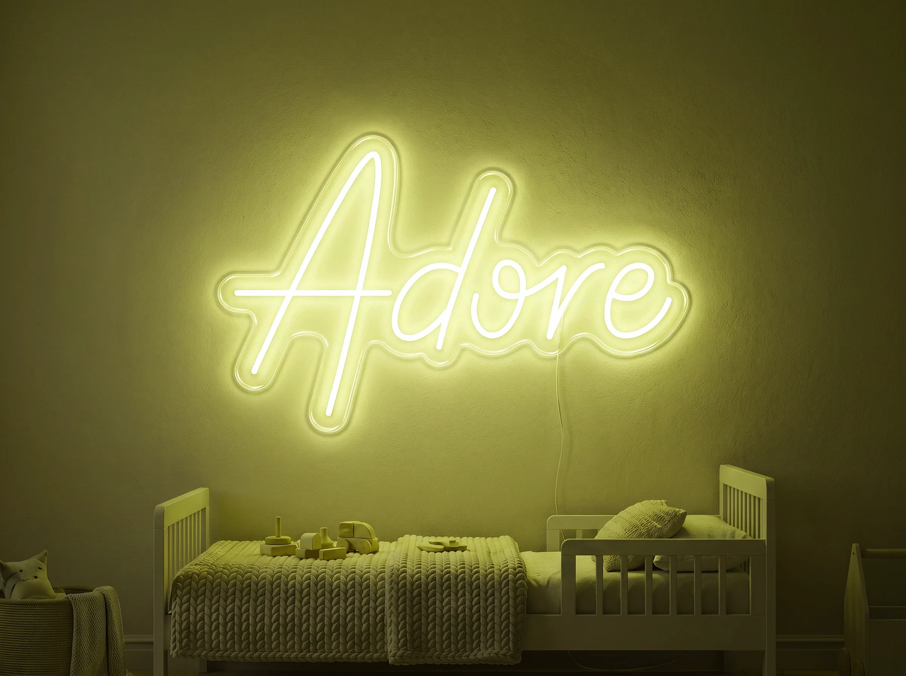 Neonskylt «Adore» i gul LED-neon, monterad på vägg