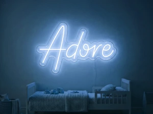 Neonskylt «Adore» i isblå LED-neon, monterad på vägg