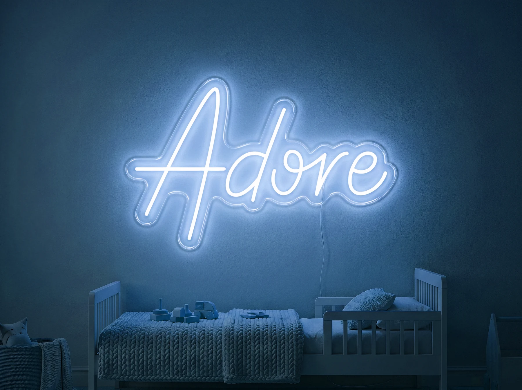 Neonskylt «Adore» i isblå LED-neon, monterad på vägg