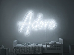 Neonskylt «Adore» i iskall vit LED-neon, monterad på vägg