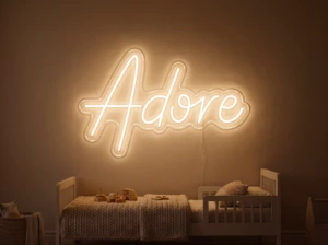 Neonskylt «Adore» i orange LED-neon, monterad på vägg