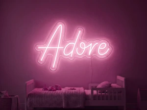 Neonskylt «Adore» i rosa LED-neon, monterad på vägg