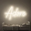 Neonskylt «Adore» i varmvit LED-neon, monterad på vägg
