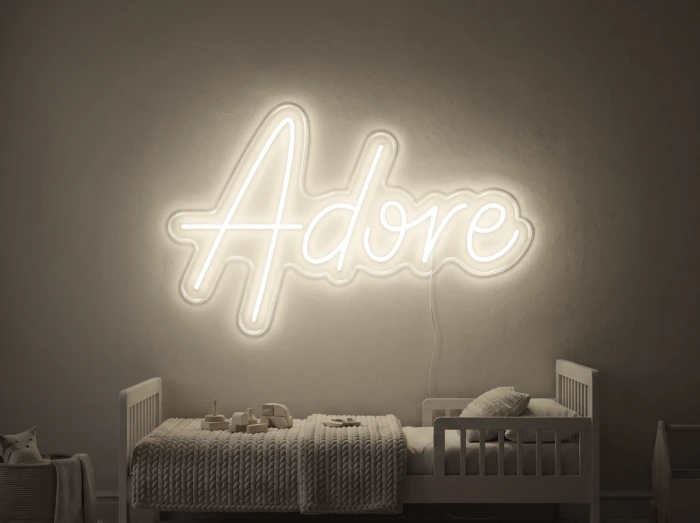 Neonskylt «Adore» i varmvit LED-neon, monterad på vägg