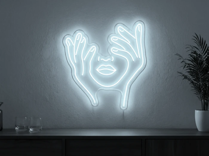 Neonskylt «Ansikte med händer» i iskall vit LED-neon, monterad på vägg