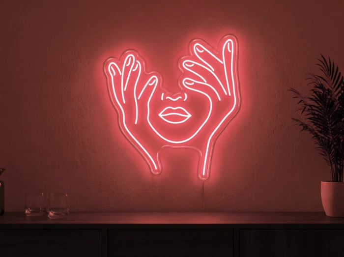 Neonskylt «Ansikte med händer» i röd LED-neon, monterad på vägg