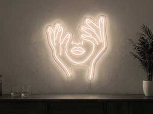 Neonskylt «Ansikte med händer» i varmvit LED-neon, monterad på vägg