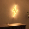 Neonskylt «Blixt» i orange LED-neon, monterad på vägg