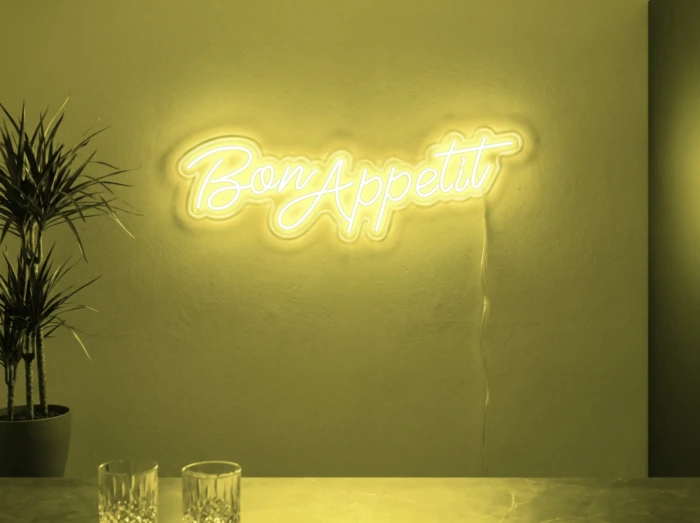 Neonskylt «Bon Appétit» i gul LED-neon, monterad på vägg