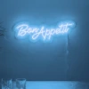 Neonskylt «Bon Appétit» i isblå LED-neon, monterad på vägg