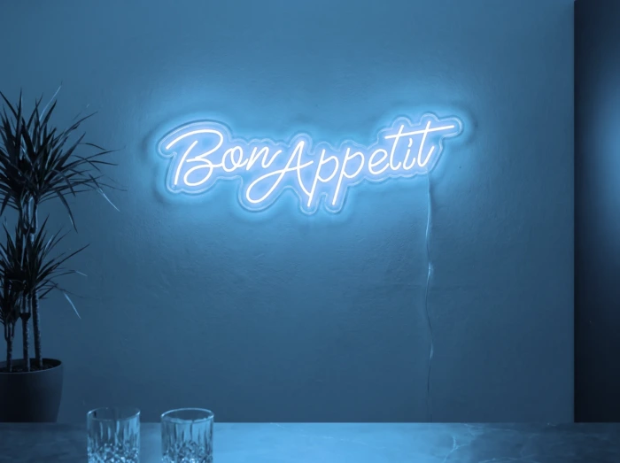 Neonskylt «Bon Appétit» i isblå LED-neon, monterad på vägg