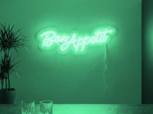 Neonskylt «Bon Appétit» i mintgrön LED-neon, monterad på vägg