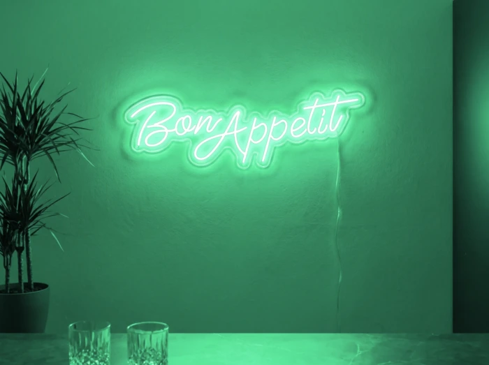Neonskylt «Bon Appétit» i mintgrön LED-neon, monterad på vägg
