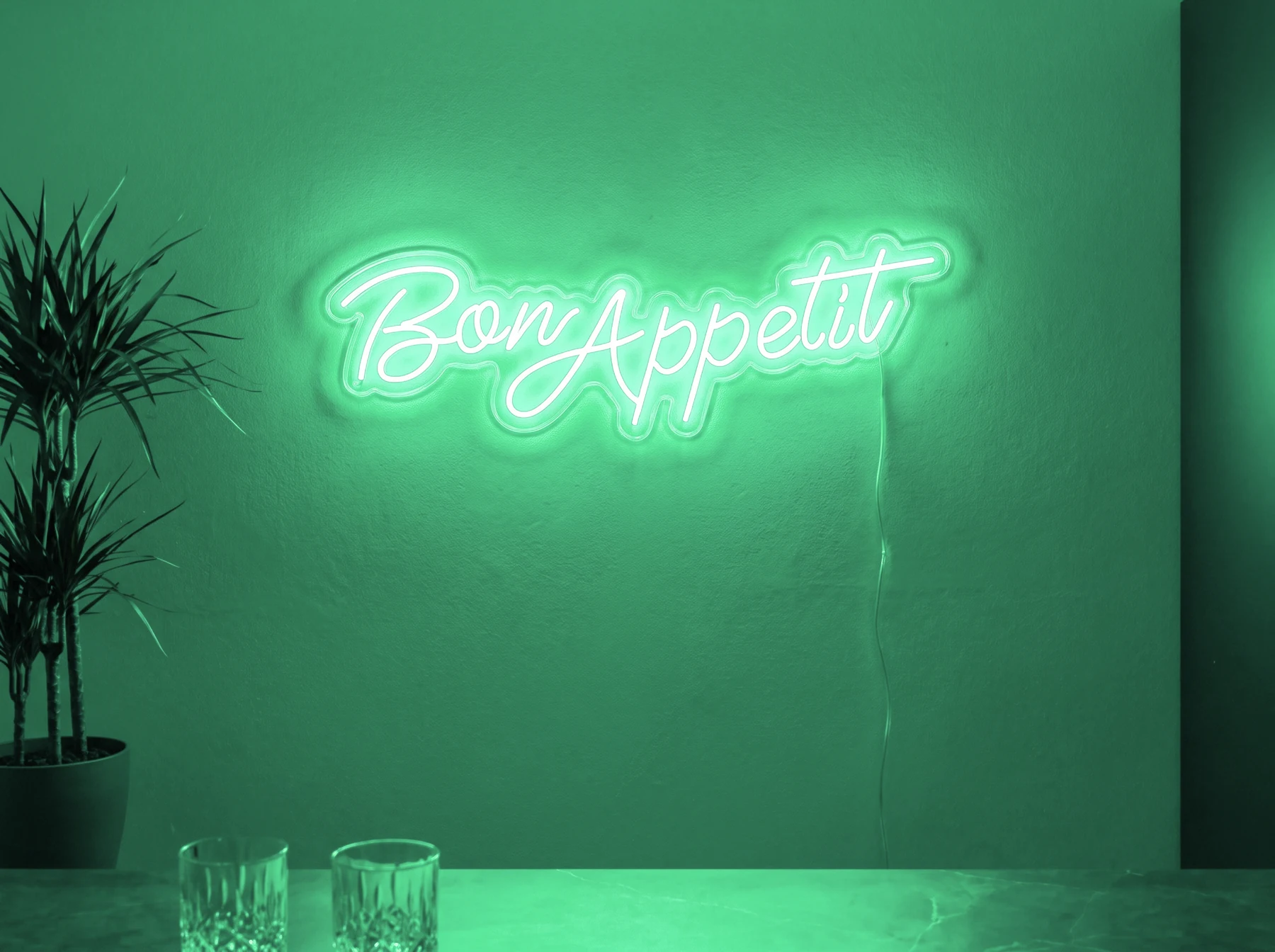 Neonskylt «Bon Appétit» i mintgrön LED-neon, monterad på vägg