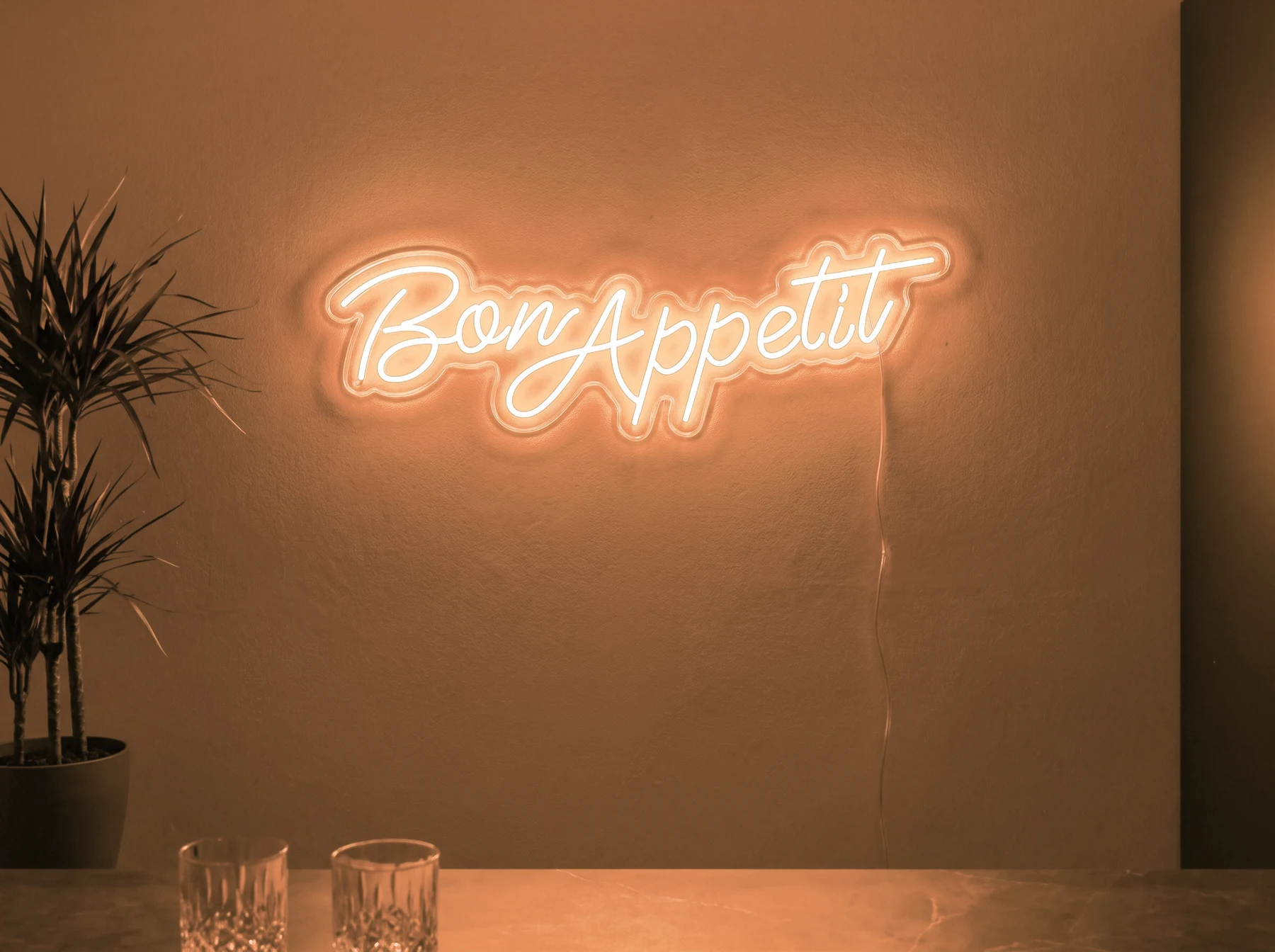 Neonskylt «Bon Appétit» i orange LED-neon, monterad på vägg