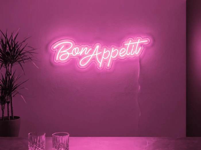 Neonskylt «Bon Appétit» i rosa LED-neon, monterad på vägg