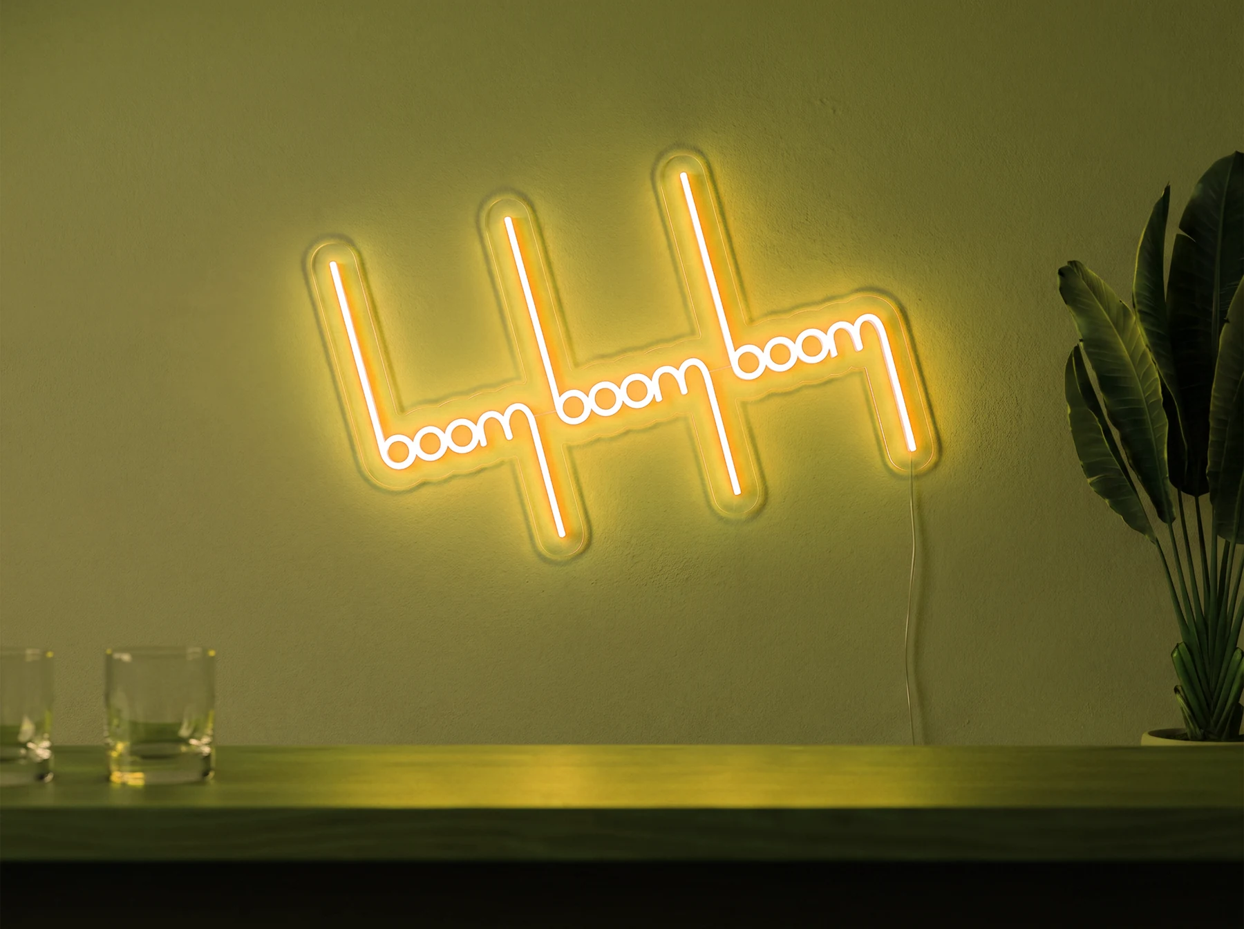 Neonskylt «Boom Boom Boom» i gul LED-neon, monterad på vägg