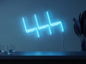 Neonskylt «Boom Boom Boom» i isblå LED-neon, monterad på vägg