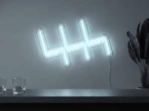 Neonskylt «Boom Boom Boom» i iskall vit LED-neon, monterad på vägg