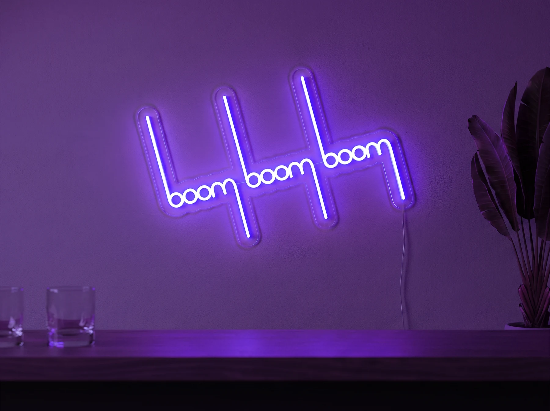 Neonskylt «Boom Boom Boom» i lila LED-neon, monterad på vägg