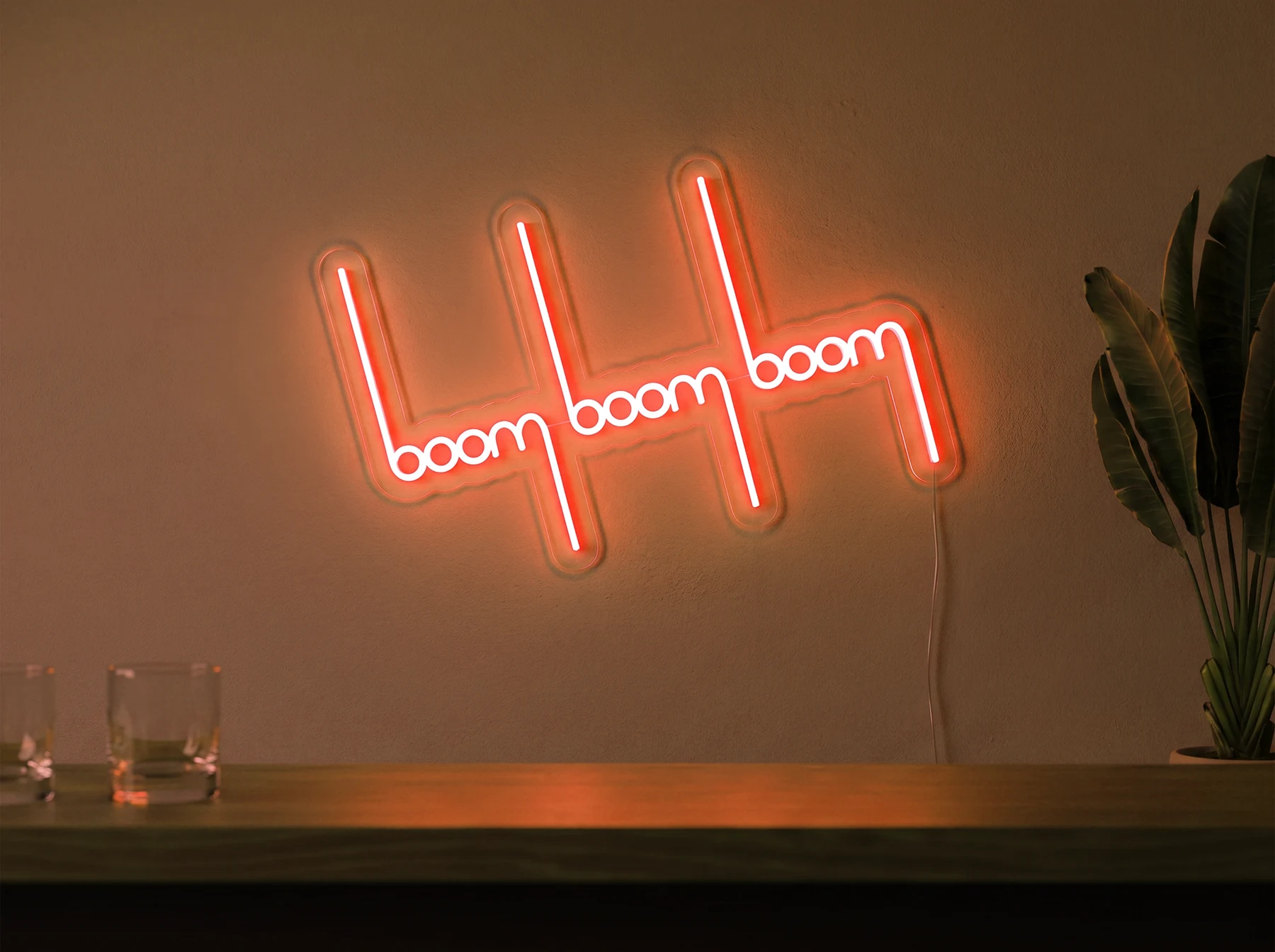 Neonskylt «Boom Boom Boom» i orange LED-neon, monterad på vägg