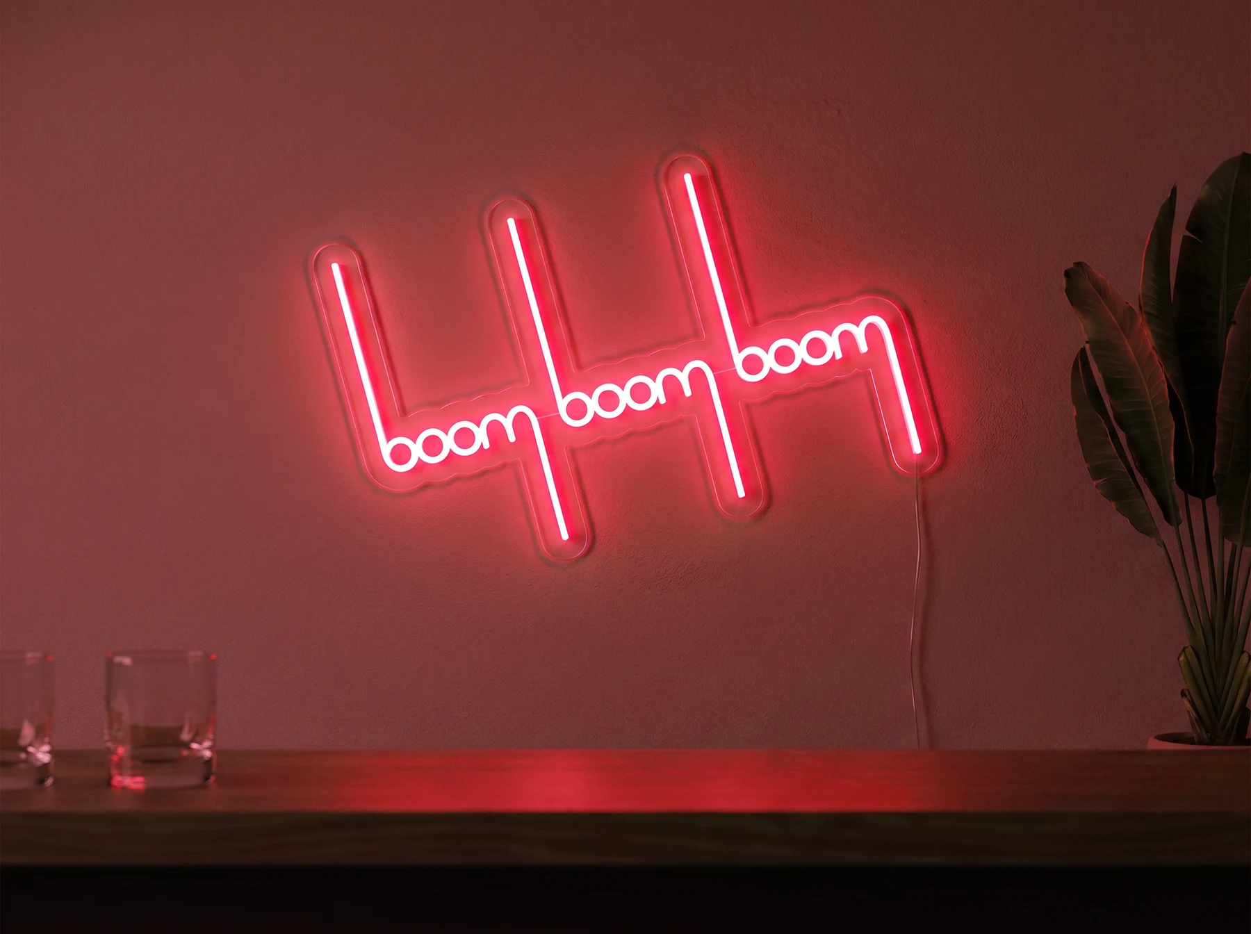 Neonskylt «Boom Boom Boom» i röd LED-neon, monterad på vägg