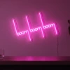 Neonskylt «Boom Boom Boom» i rosa LED-neon, monterad på vägg