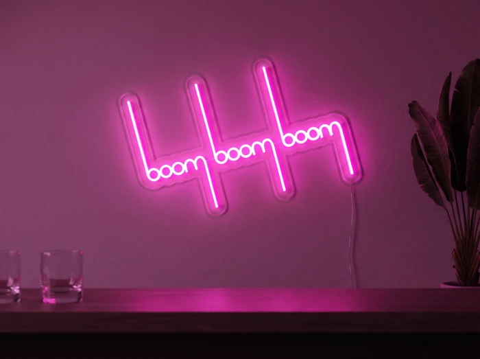 Neonskylt «Boom Boom Boom» i rosa LED-neon, monterad på vägg