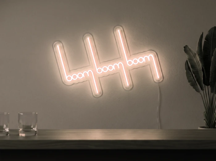 Neonskylt «Boom Boom Boom» i varmvit LED-neon, monterad på vägg