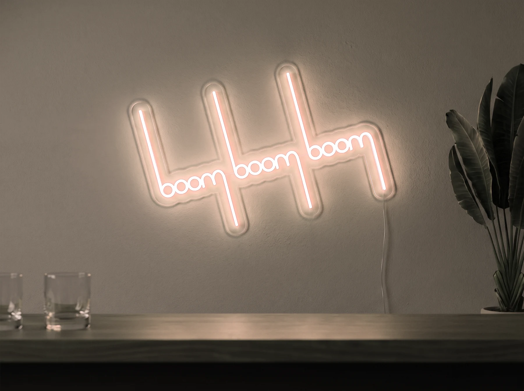 Neonskylt «Boom Boom Boom» i varmvit LED-neon, monterad på vägg