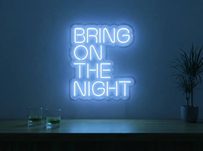 Neonskylt «Bring On The Night» i isblå LED-neon, monterad på vägg