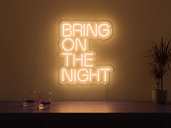 Neonskylt «Bring On The Night» i orange LED-neon, monterad på vägg