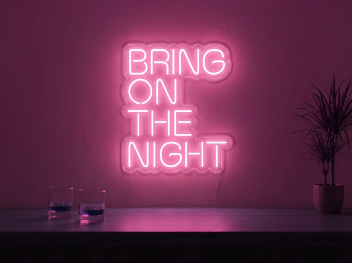 Neonskylt «Bring On The Night» i rosa LED-neon, monterad på vägg