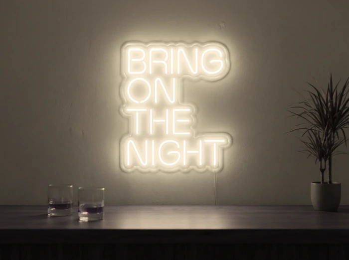 Neonskylt «Bring On The Night» i varmvit LED-neon, monterad på vägg