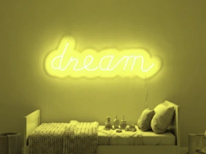 Neonskylt «Dream» i gul LED-neon, monterad på vägg