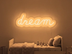 Neonskylt «Dream» i orange LED-neon, monterad på vägg