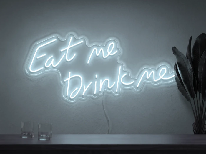 Neonskylt «Eat Me Drink Me» i iskall vit LED-neon, monterad på vägg