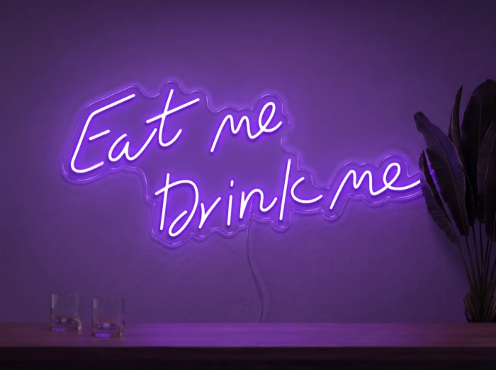 Neonskylt «Eat Me Drink Me» i lila LED-neon, monterad på vägg