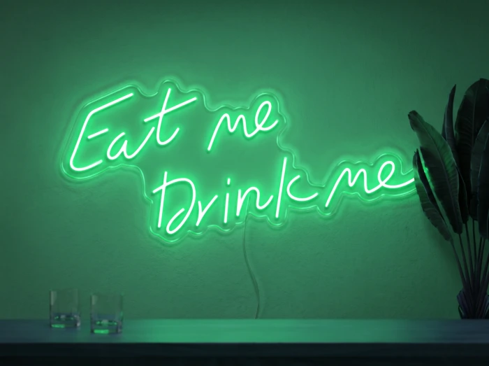 Neonskylt «Eat Me Drink Me» i mintgrön LED-neon, monterad på vägg