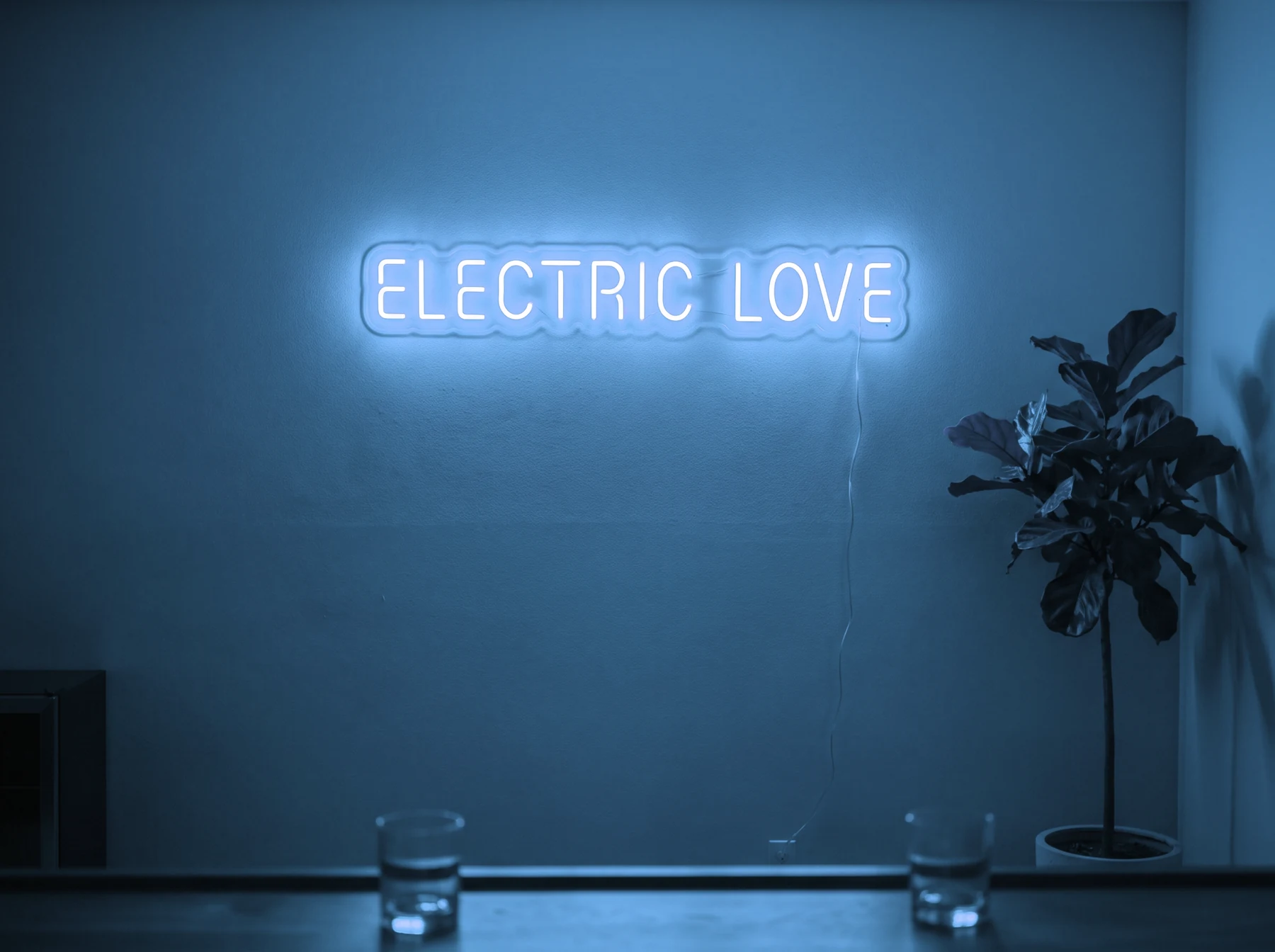 Neonskylt «Electric Love» i isblå LED-neon, monterad på vägg