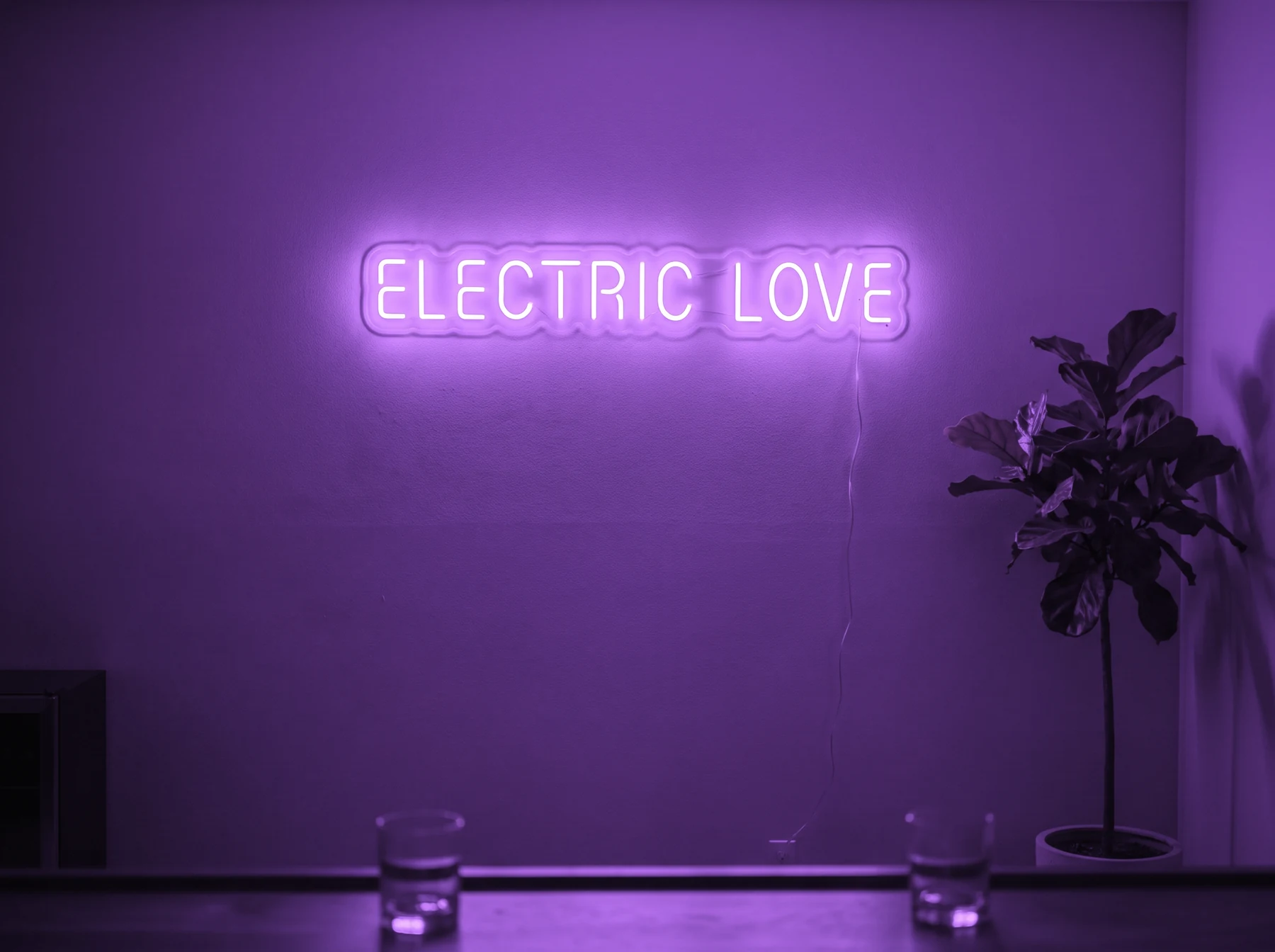 Neonskylt «Electric Love» i lila LED-neon, monterad på vägg
