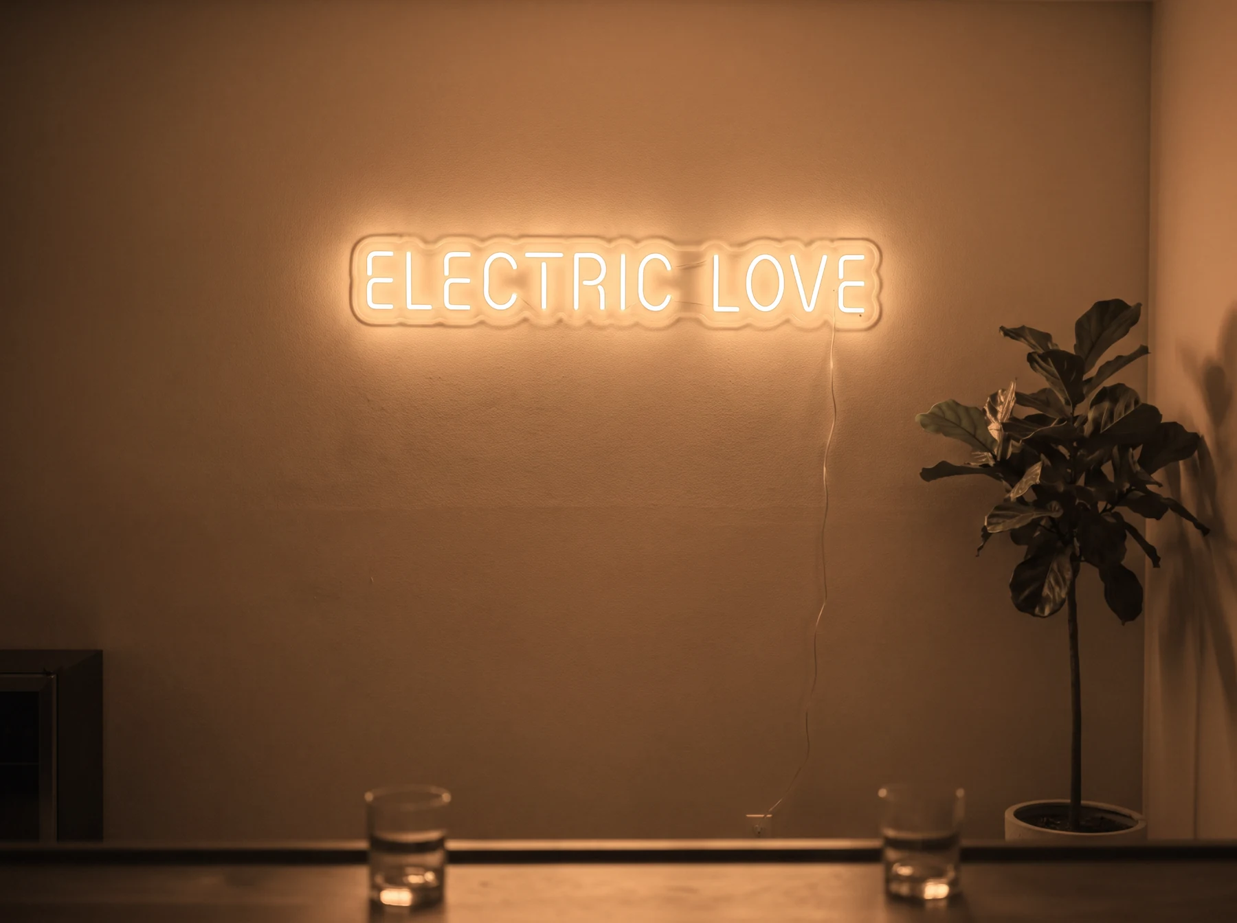 Neonskylt «Electric Love» i orange LED-neon, monterad på vägg