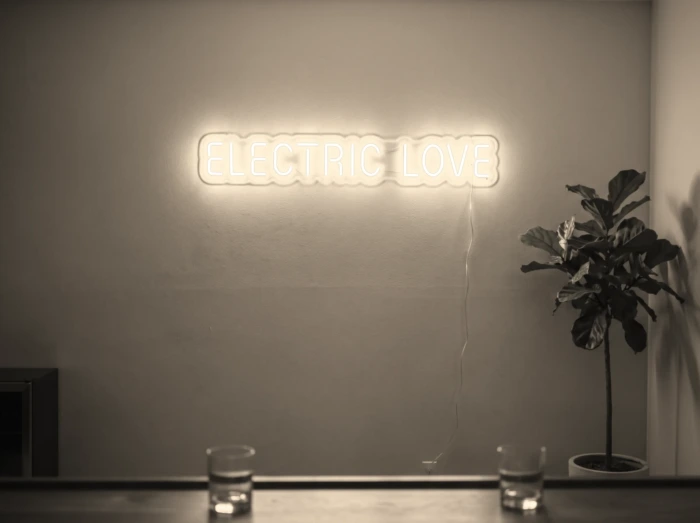 Neonskylt «Electric Love» i varmvit LED-neon, monterad på vägg