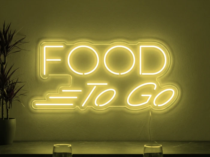 Neonskylt «Food To Go» i gul LED-neon, monterad på vägg