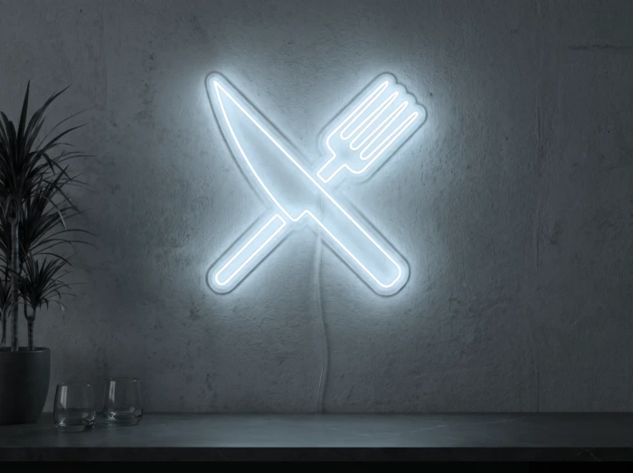 Neonskylt «Gaffel och kniv» i iskall vit LED-neon, monterad på vägg