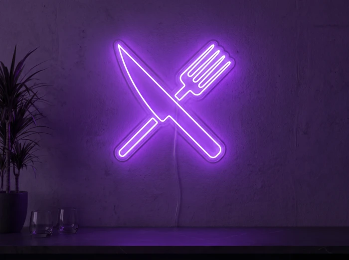 Neonskylt «Gaffel och kniv» i lila LED-neon, monterad på vägg