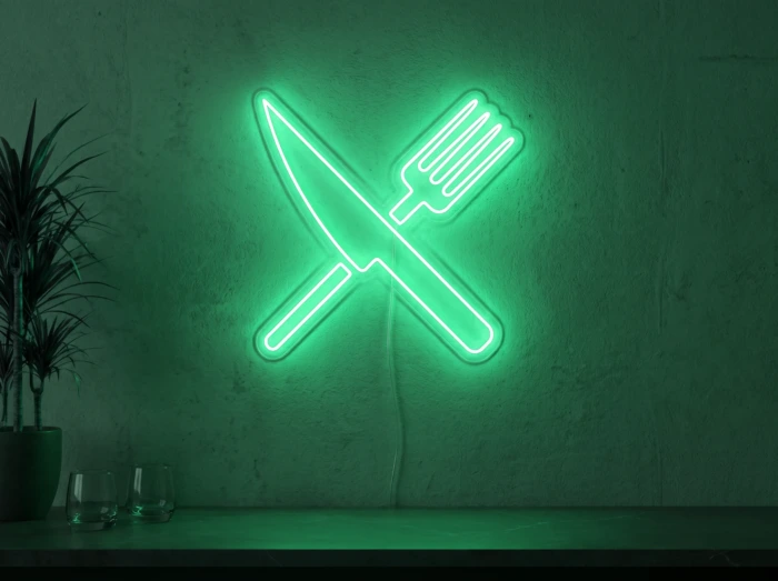 Neonskylt «Gaffel och kniv» i mintgrön LED-neon, monterad på vägg
