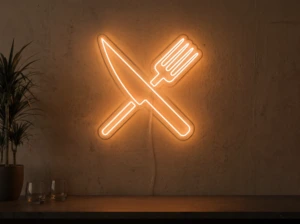 Neonskylt «Gaffel och kniv» i orange LED-neon, monterad på vägg