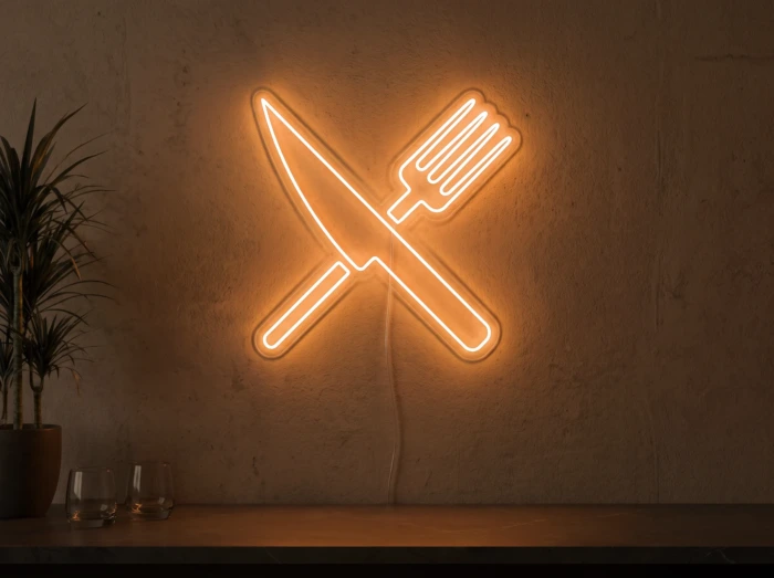 Neonskylt «Gaffel och kniv» i orange LED-neon, monterad på vägg